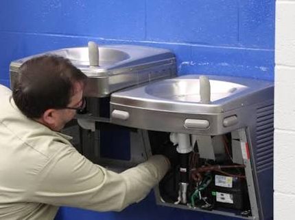 Technicien P2O installant une fontaine à eau murale