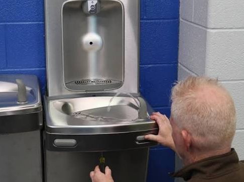 Technicien P2O réparant une fontaine à eau murale