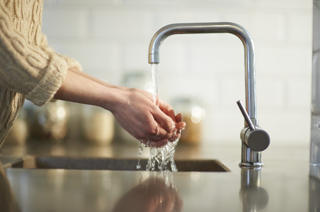 Eau filtrée coulant d'un robinet de cuisine dans les mains
