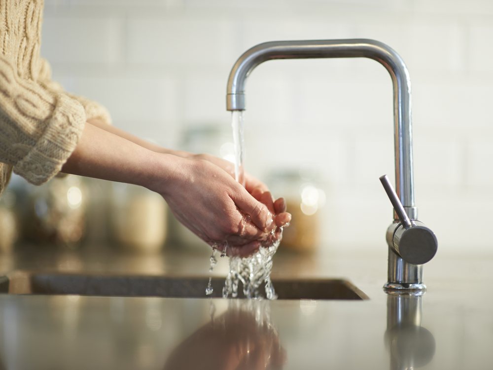 Eau filtrée coulant d'un robinet de cuisine dans les mains
